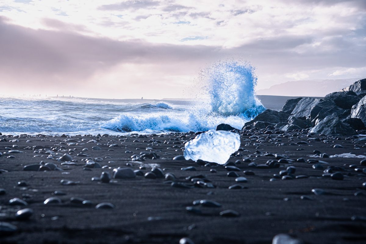 Glacier ice on the black beach, wave breaking